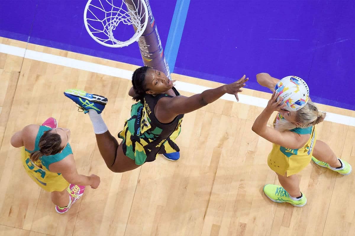 An action photo taken from high above the net, showing three women playing netball